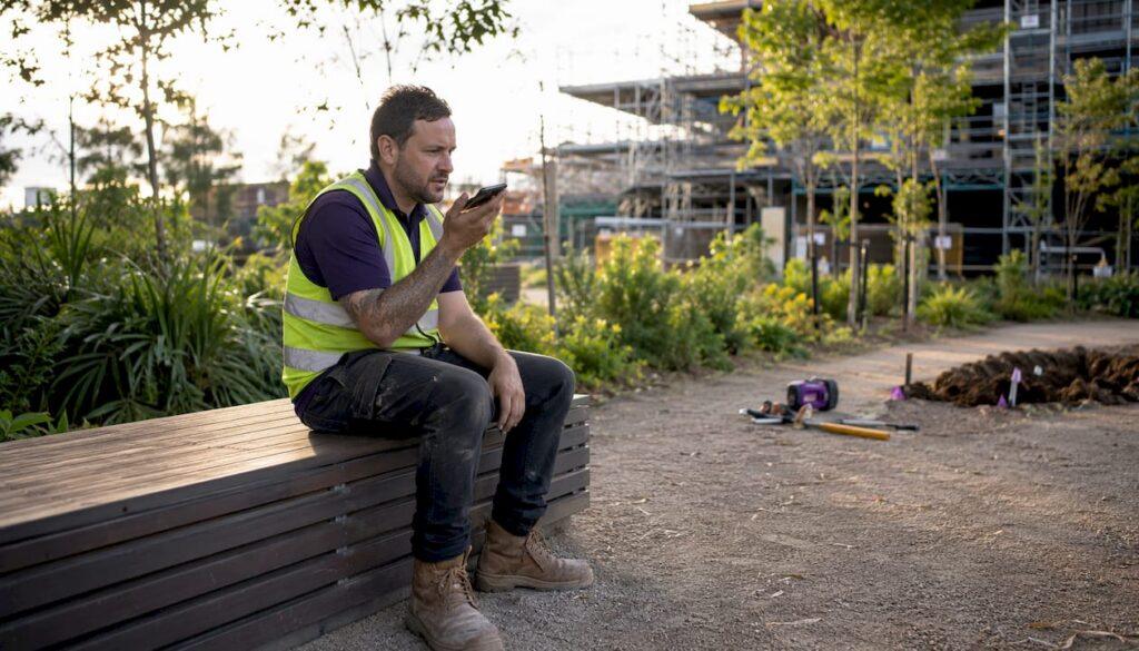 Australian tradesman using smartphone with voice commands at job site