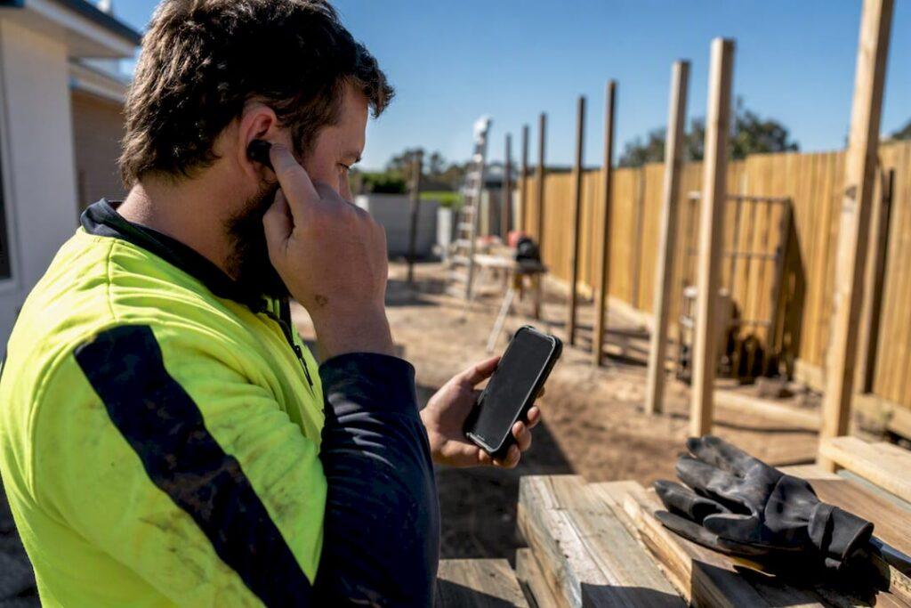 Tradie adjusting Bluetooth headset at worksite