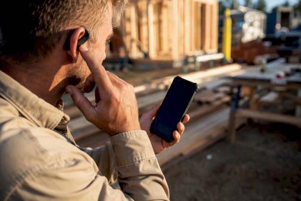 Hands adjusting wireless earpiece outdoors