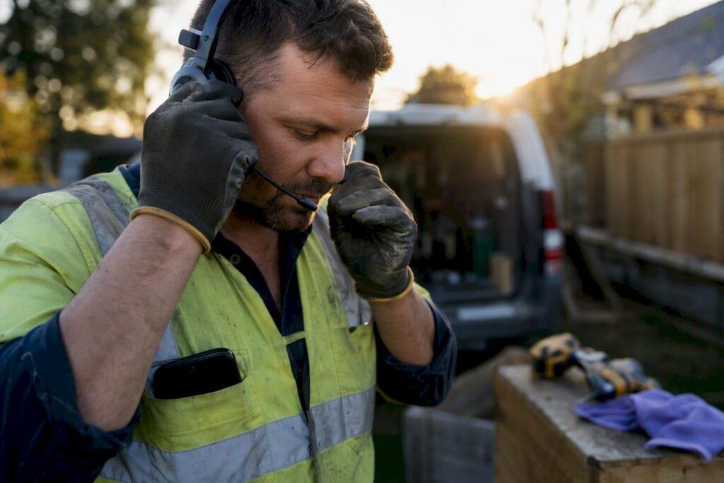 Tradie adjusting headset microphone outdoors